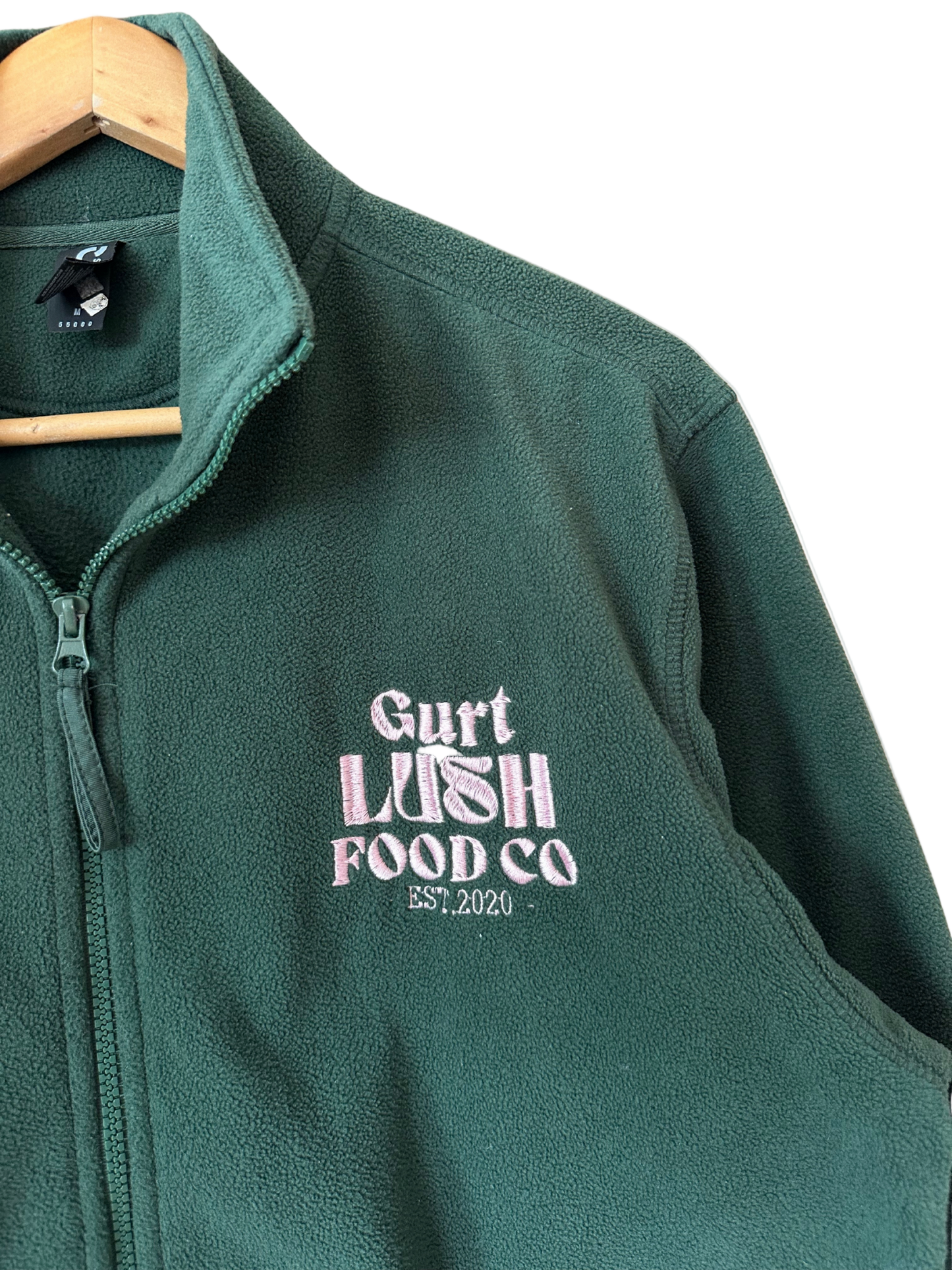 Green fleece jacket with 'Gurt Lush Food Co' logo on a white background