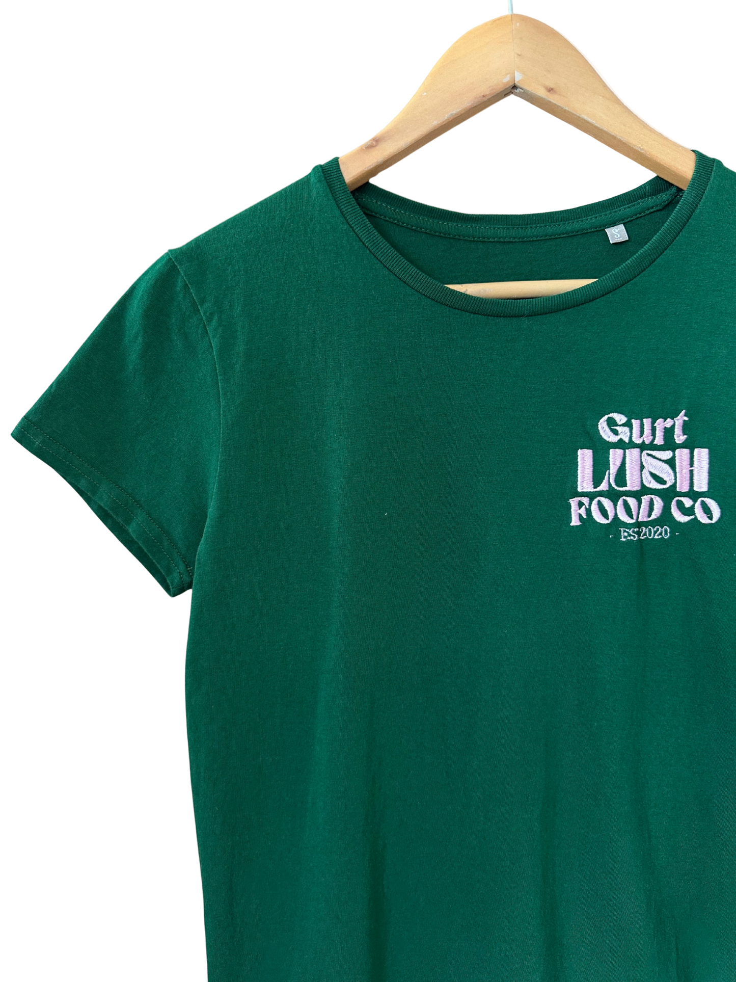 Green t-shirt with 'Gurt Lush Food Co' text on a hanger