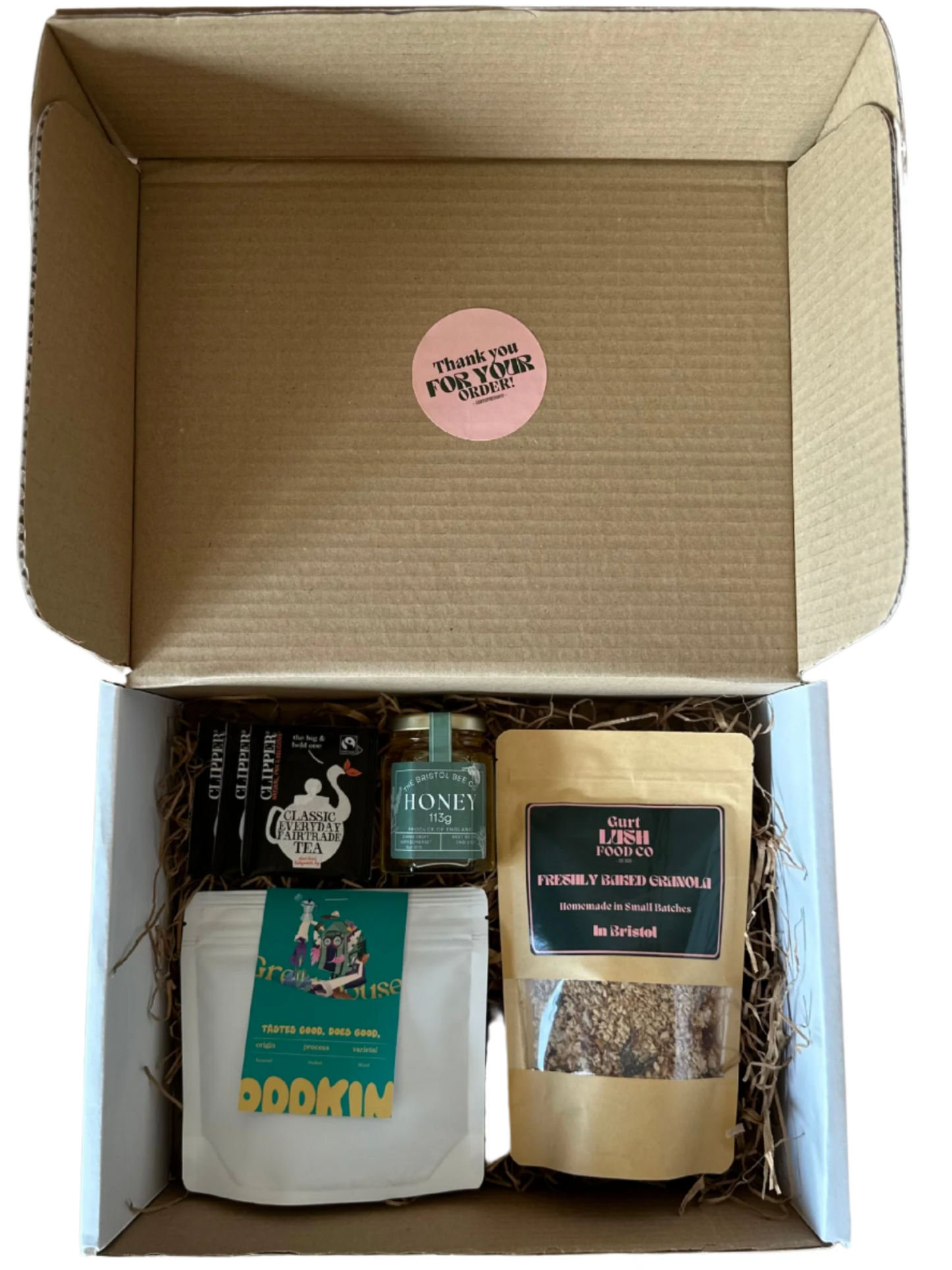 Open cardboard box containing various items including a bottle, a jar, and a bag with a visible brand label.