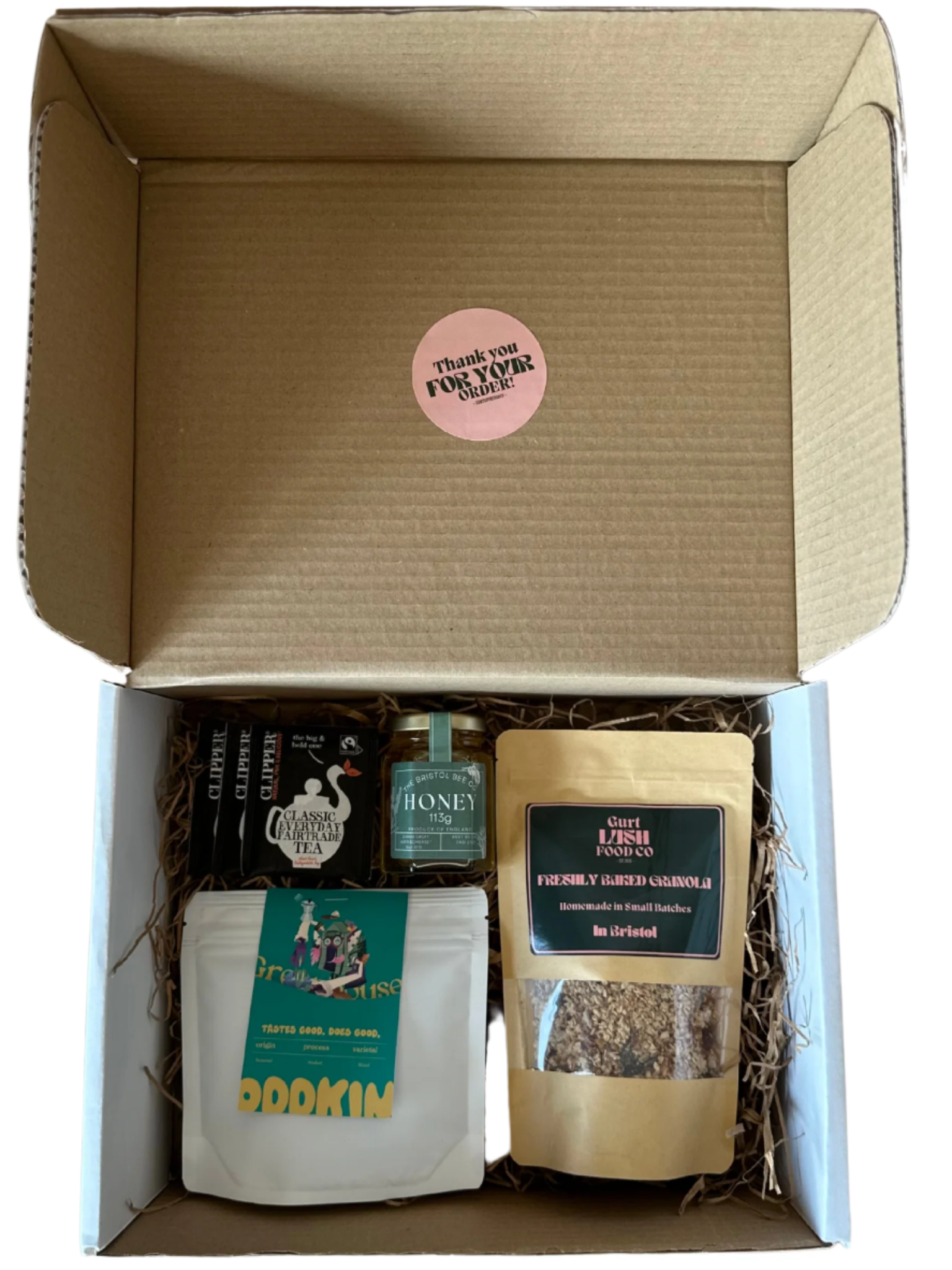 Open cardboard box containing various items including a bottle, a jar, and a bag with a visible brand label.