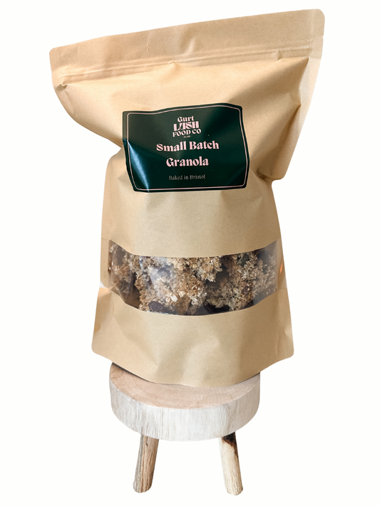 Bag of small batch granola on a wooden stand with a white background