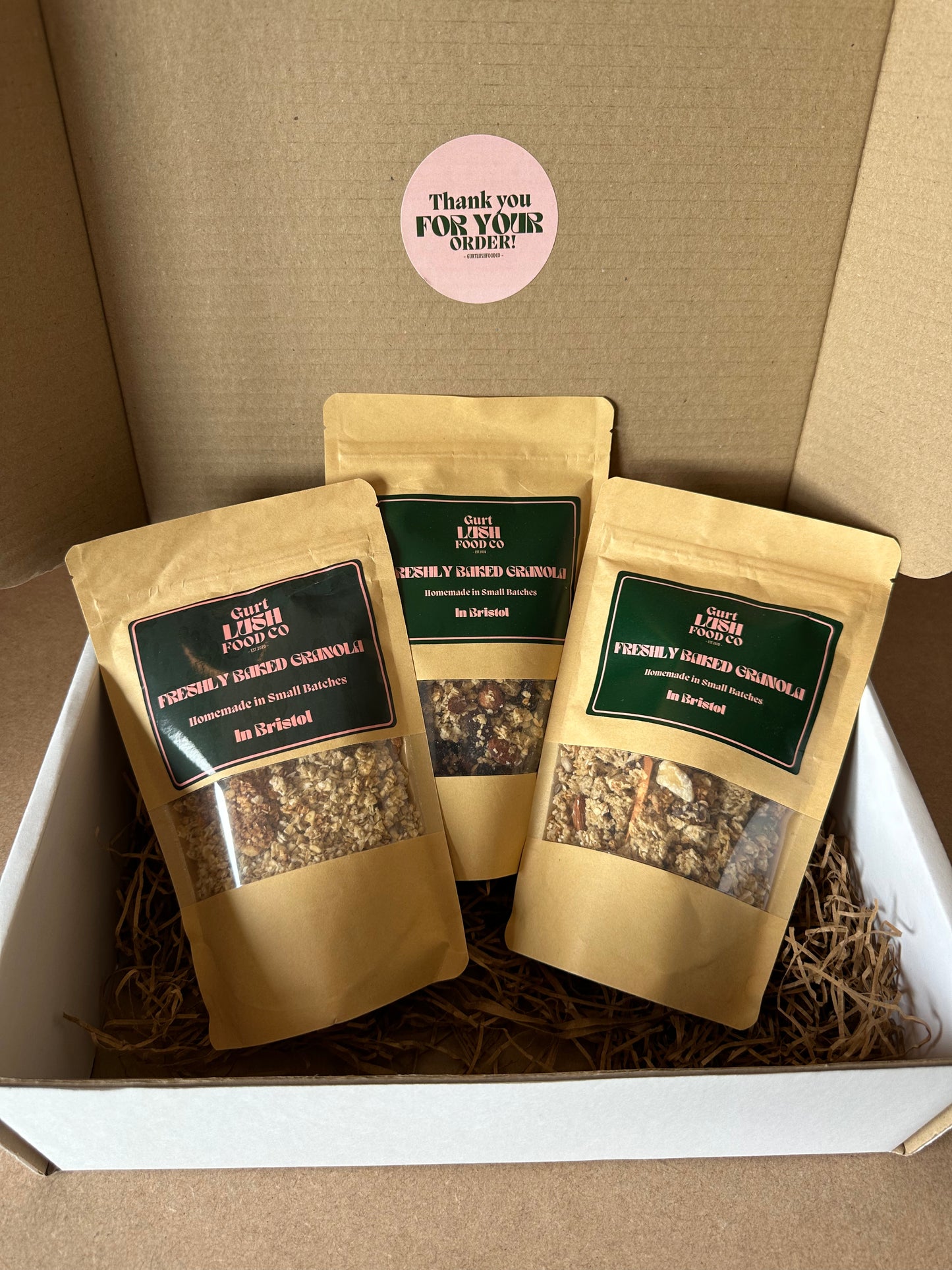 Three granola bags in packaging with a visible brand label on a brown background.
