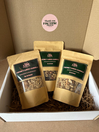 Three granola bags in packaging with a visible brand label on a brown background.